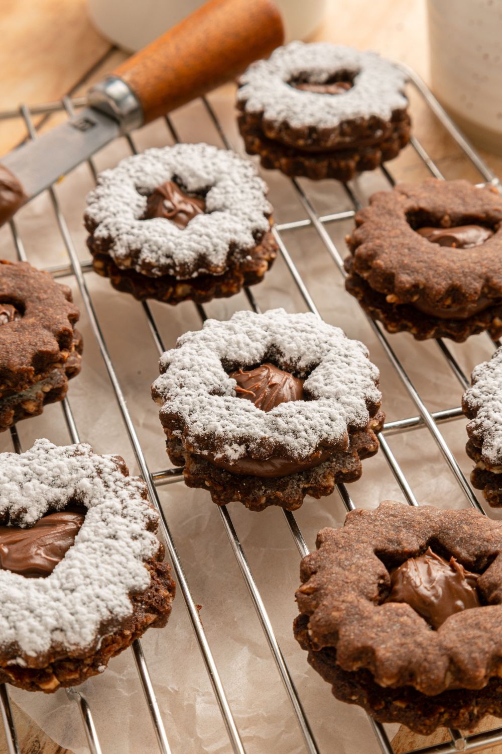 Chocolate Linzer Cookies spread out on the table some dusted with powdered sugar on a metal cooling rack 
