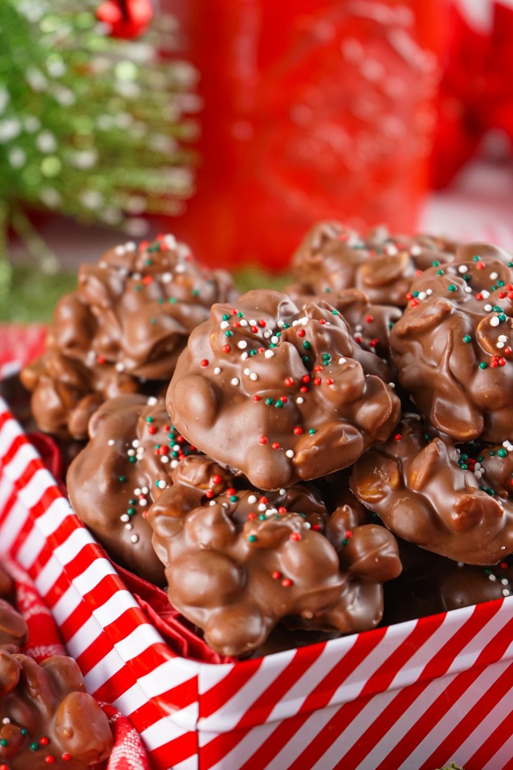 side view of a candy tin on table that is overfull of Crockpot Christmas Candy