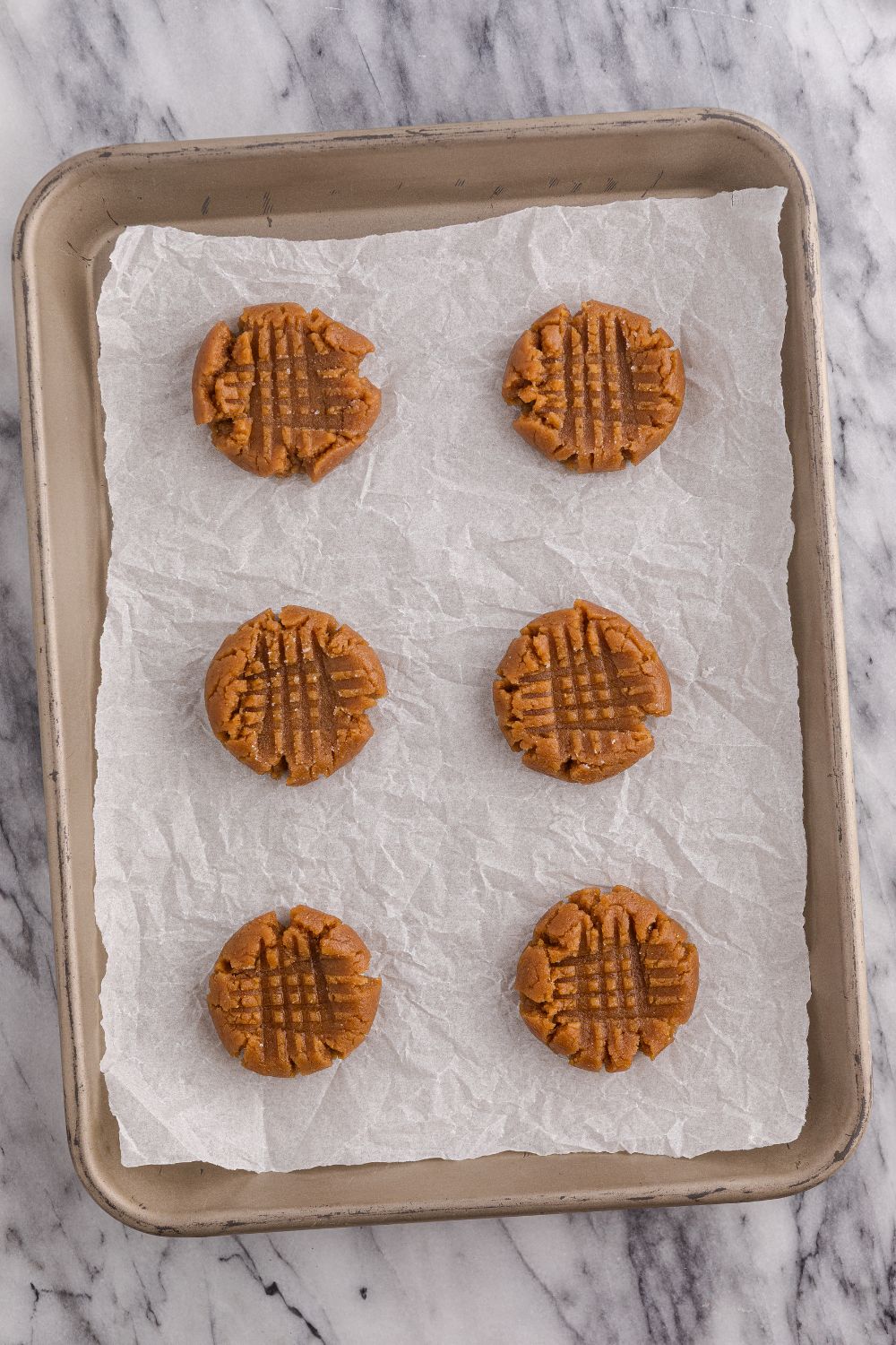 raw peanut butter cookies on the cookie sheet tray
