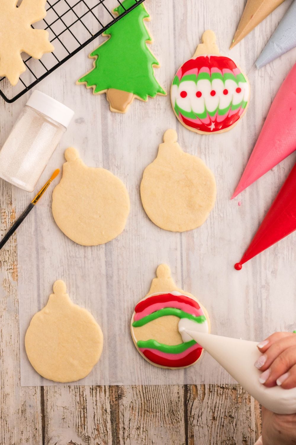 christmas ornament shaped and being piped with royal icing to decorate