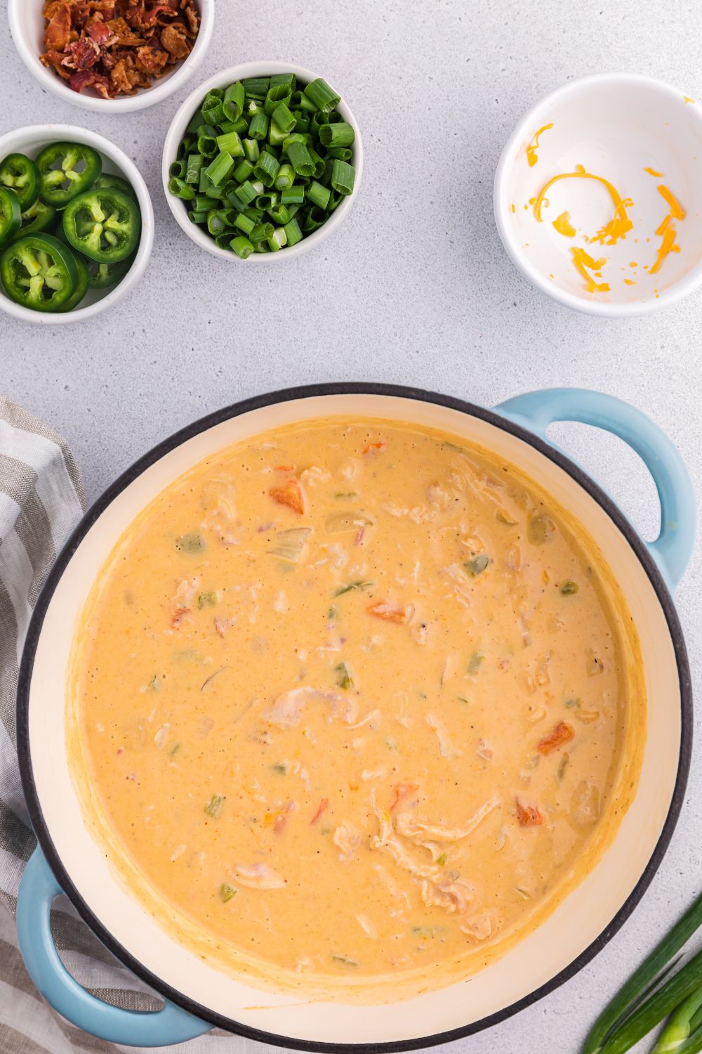 jalapeño popper crack chicken soup in a pot with small bowls of ingredients around for toppers