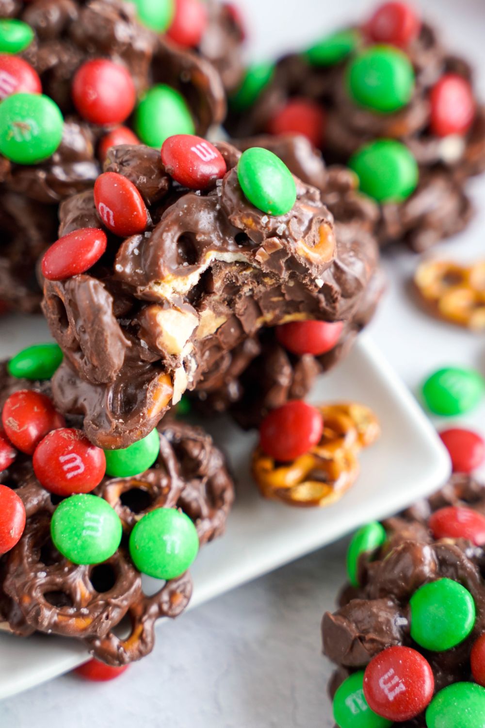 Crockpot Chocolate Pretzel Christmas Candy on a white platter with a bite taken out of it