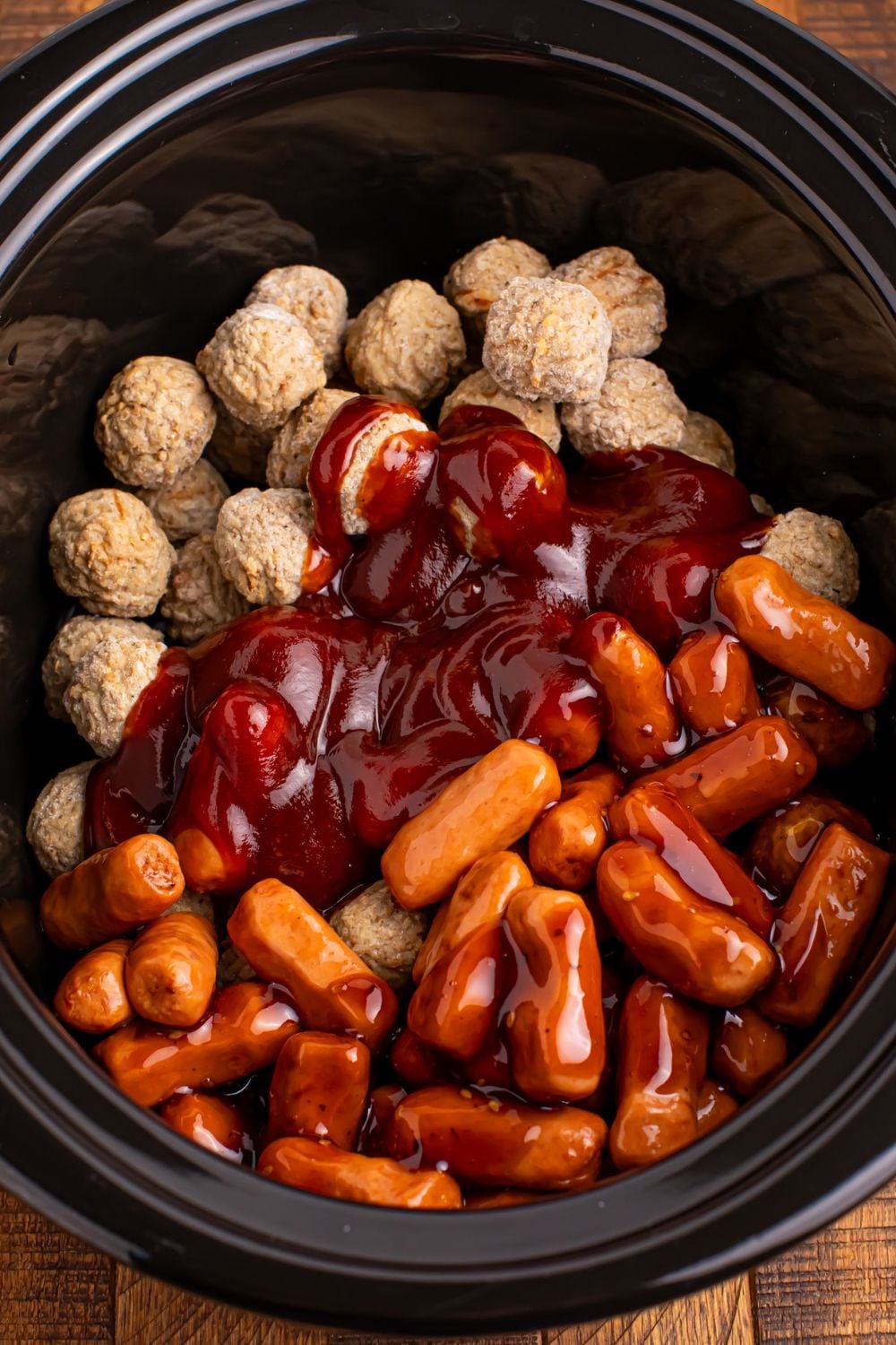 Crockpot Teriyaki BBQ Cocktail Meatballs & Lil Smokies being dumped into a slow cooker and yet to be stirred up