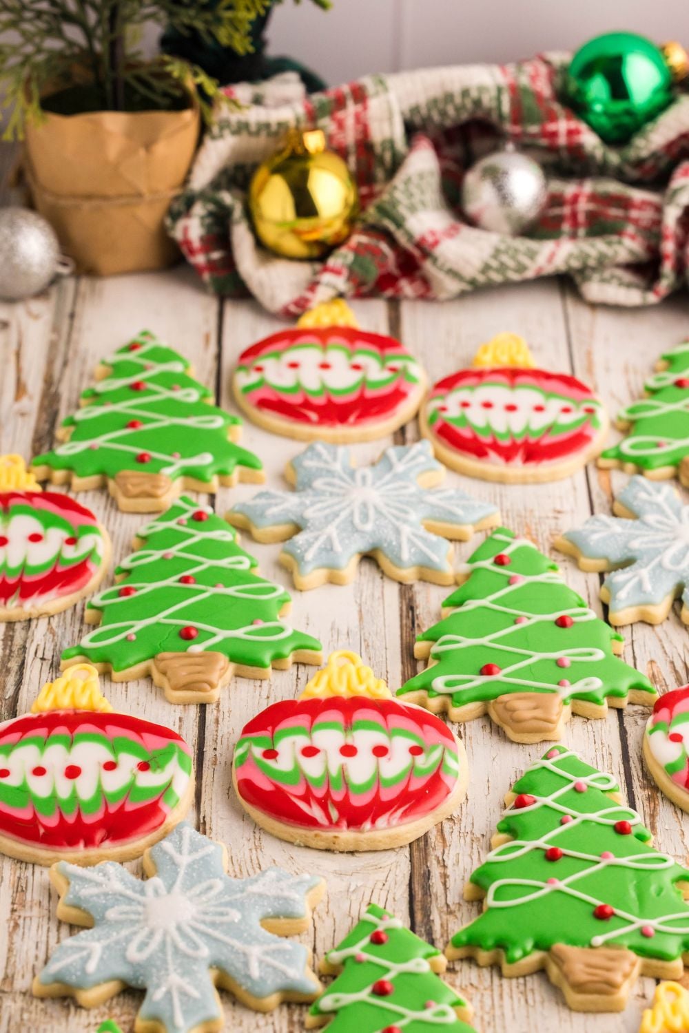 Decorated Sugar Cookies placed all around the table with Christmas ornaments and other holiday decorations at the back of table
