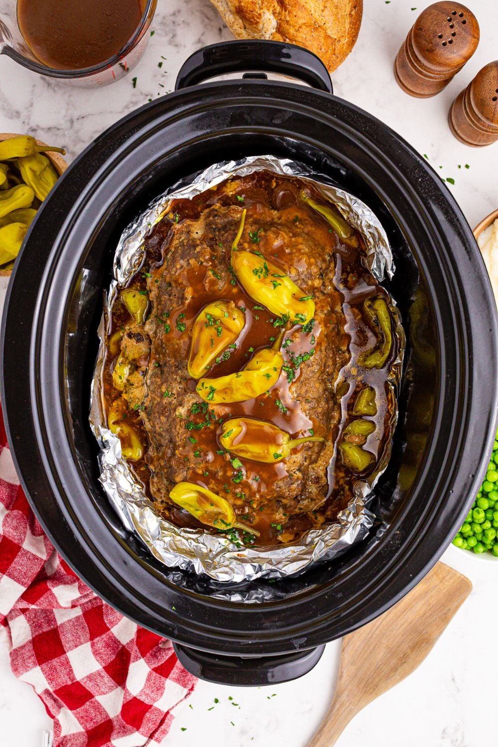 looking down on table to see Crockpot Mississippi Meatloaf with a red checkered towel to side