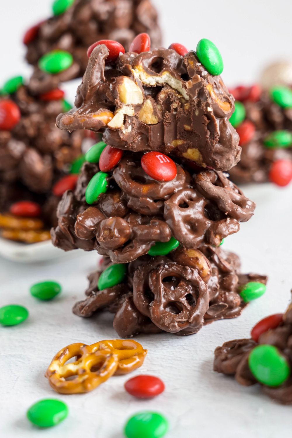 Crockpot Chocolate Pretzel Christmas Candy spread around table with some candies stacking up