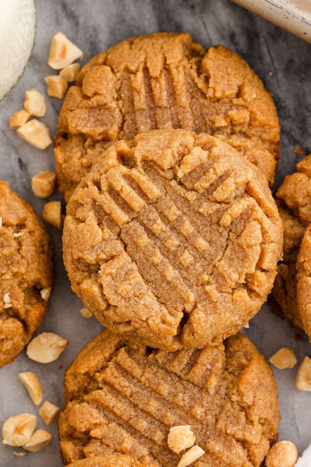 close up of peanut butter cookies on a marble counter with peanuts around the table
