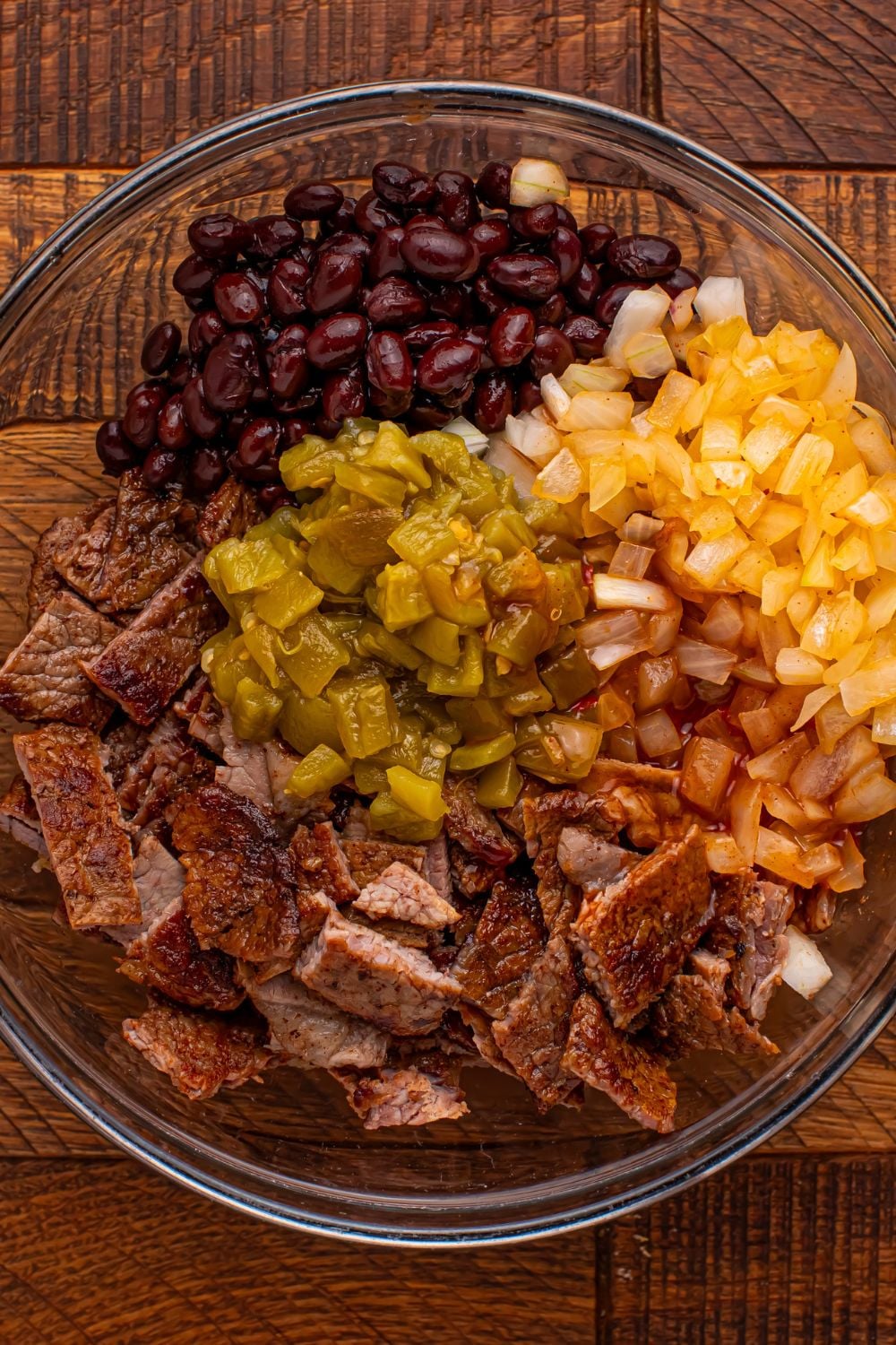steak mixture in a glass bowl on wooden table for making Steak Enchiladas
