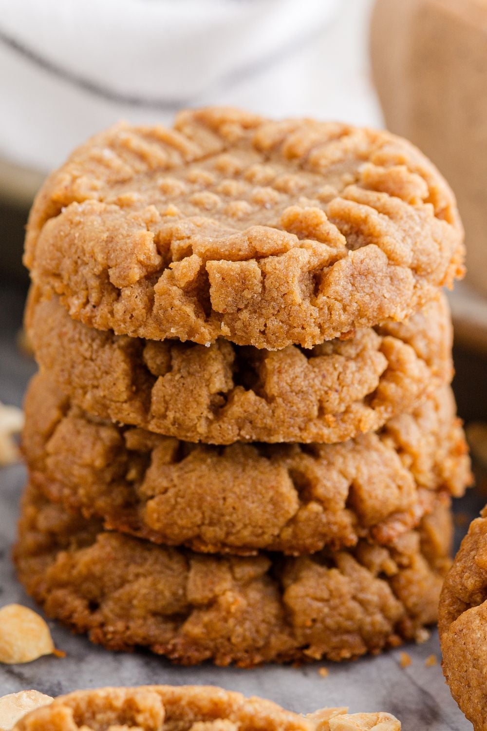 4 Ingredient Peanut Butter Cookies stacked on the table with some nuts around the table