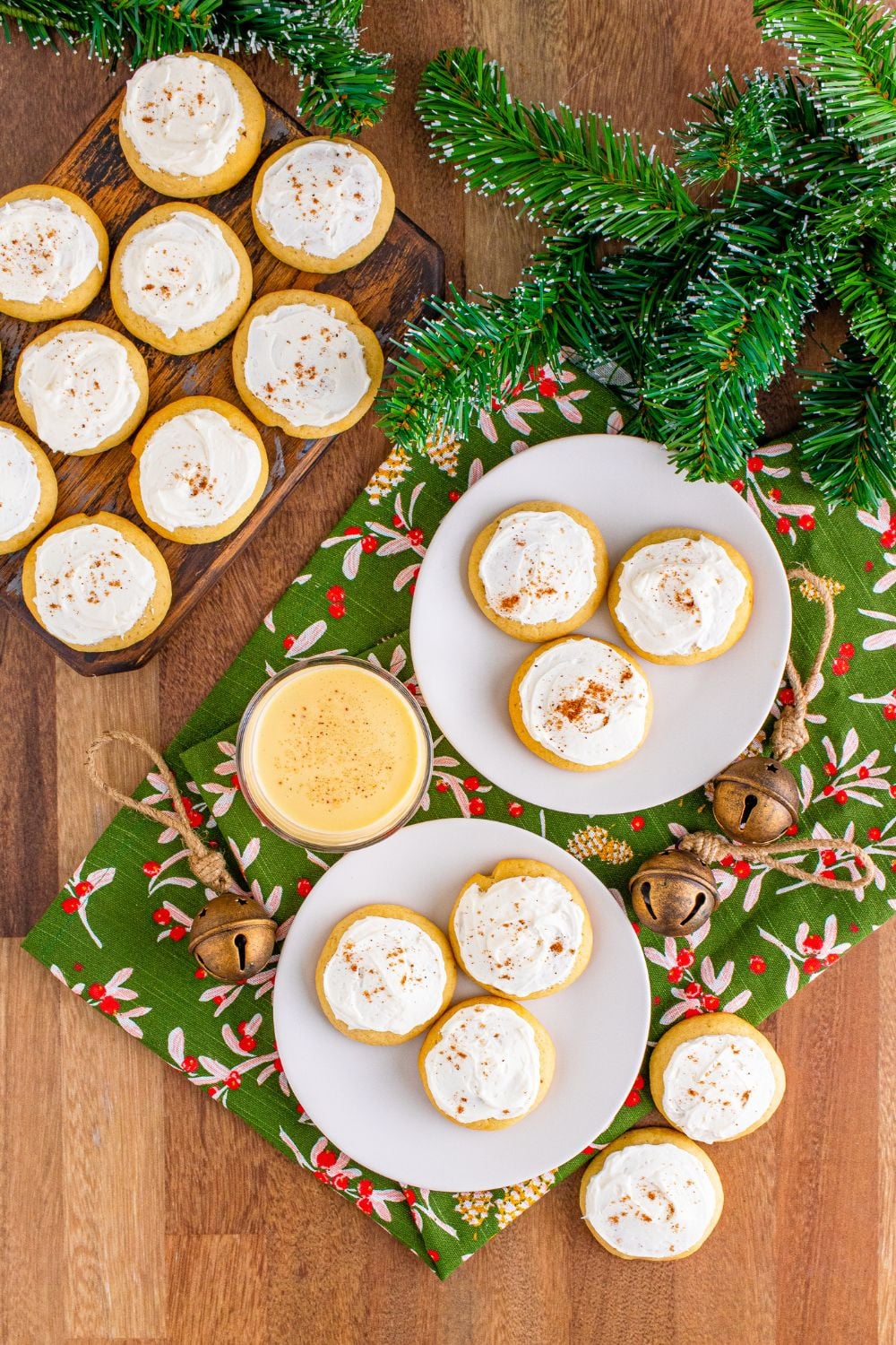 Soft Frosted Eggnog Cookies on plates on a table and a wooden table to side with more cookies