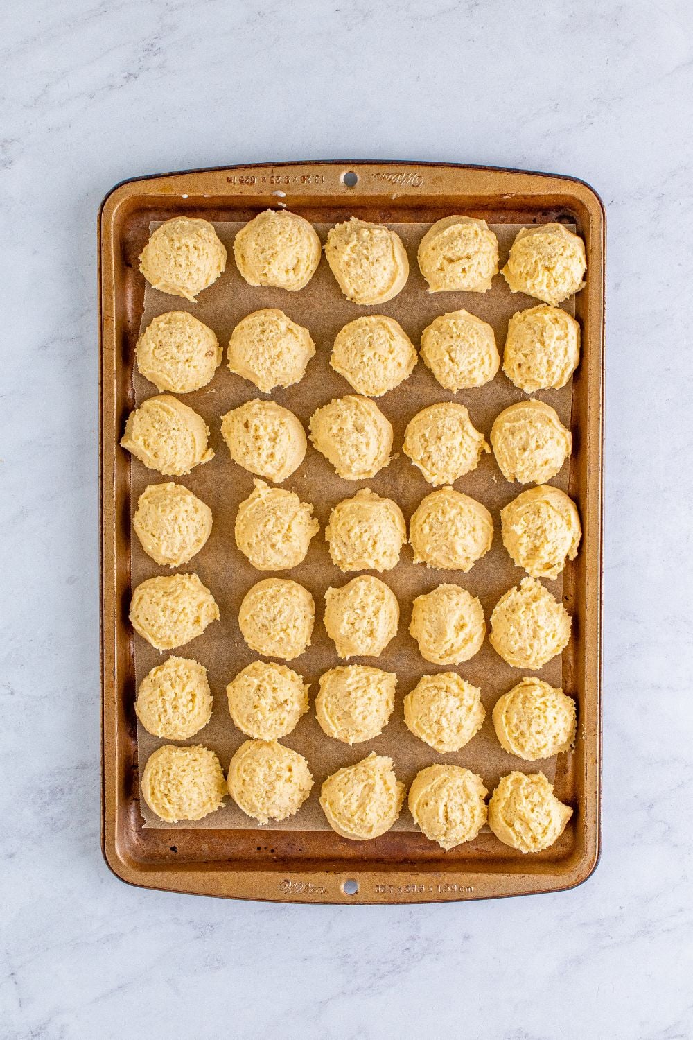 raw eggnog cookie dough balls on a baking sheet on table