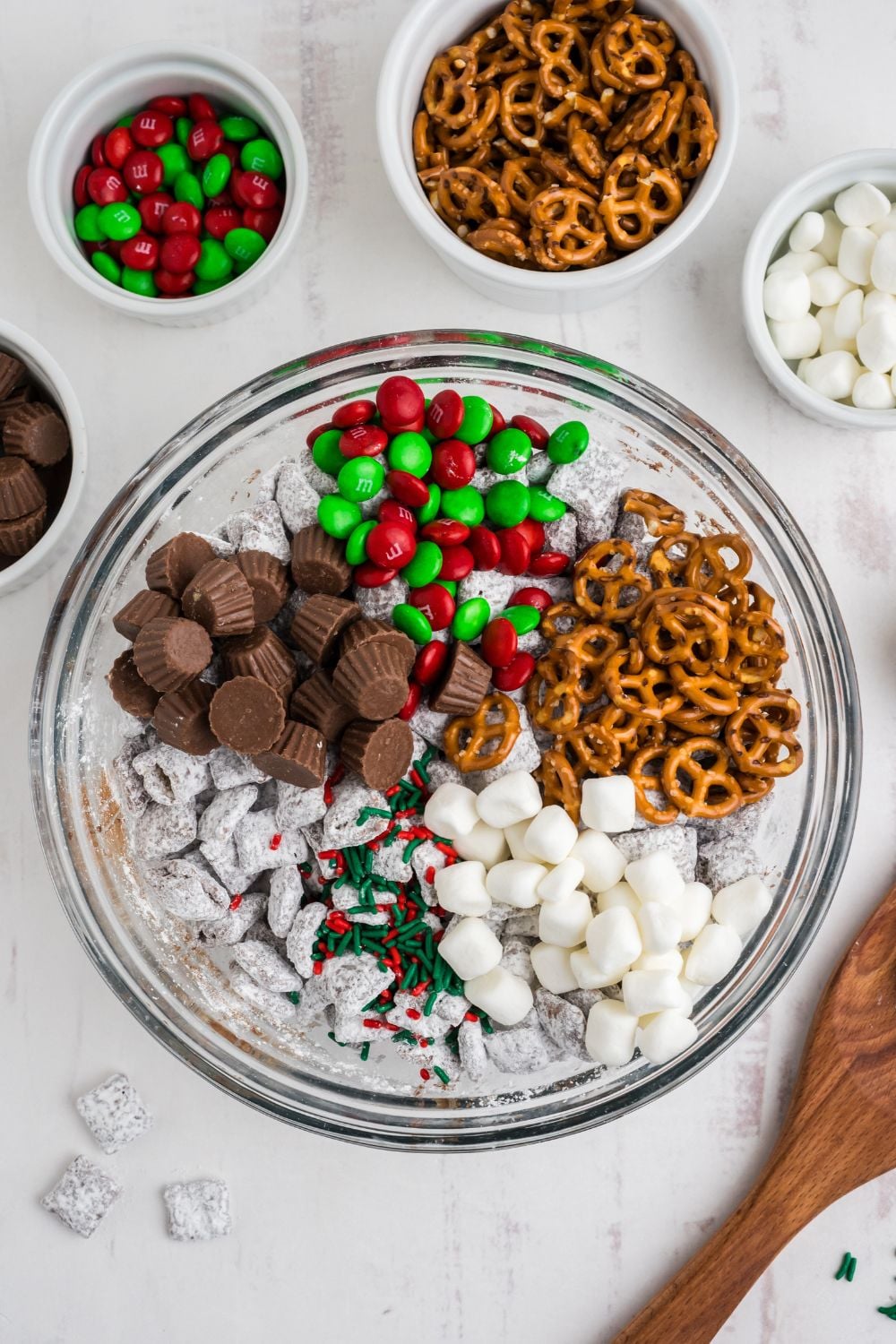 all the mix in ingredients for Christmas Chex Mix sitting on top of a bowl of puppy chow