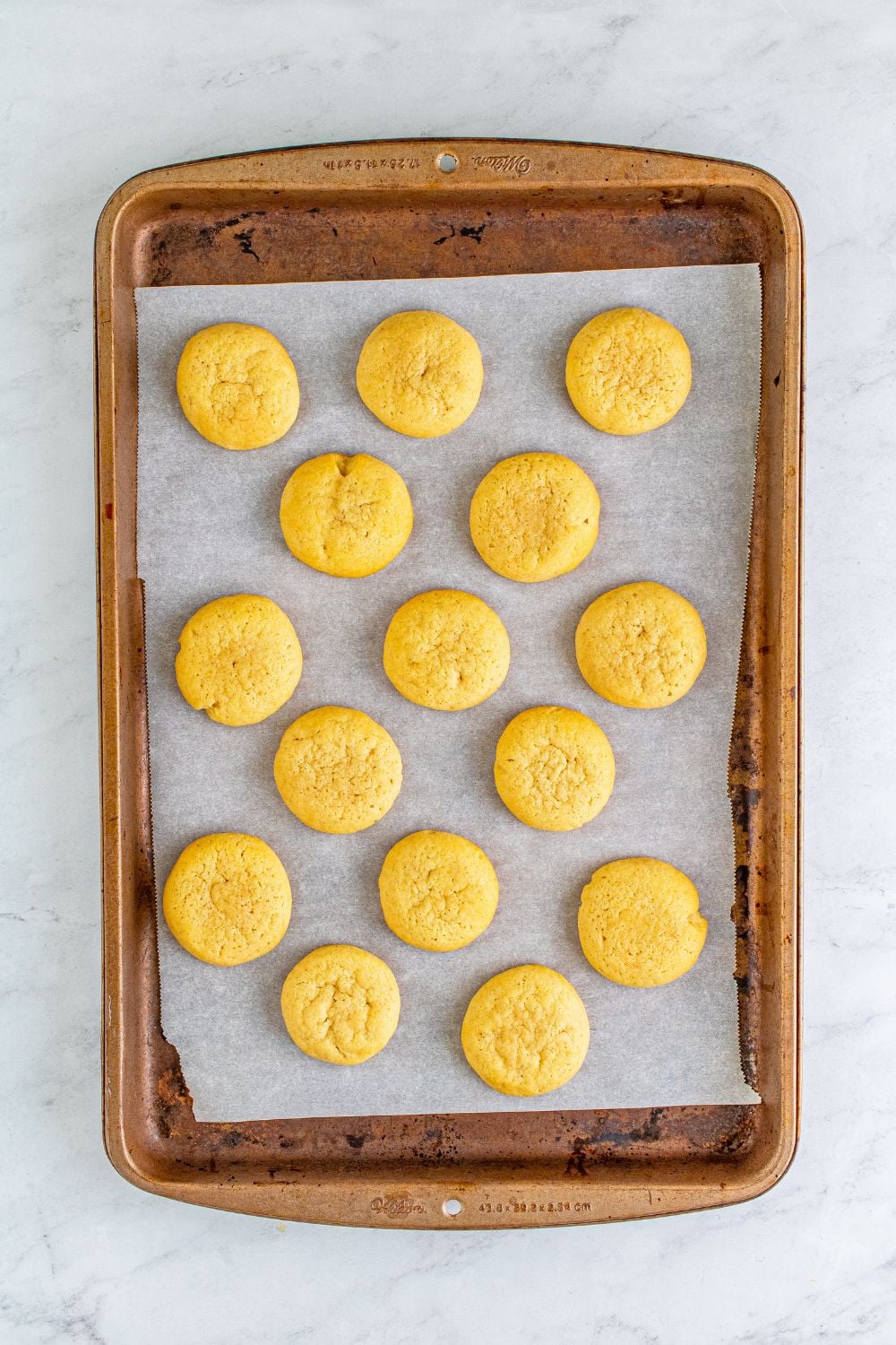 baked cookies on a cookie sheet on table with parchment paper