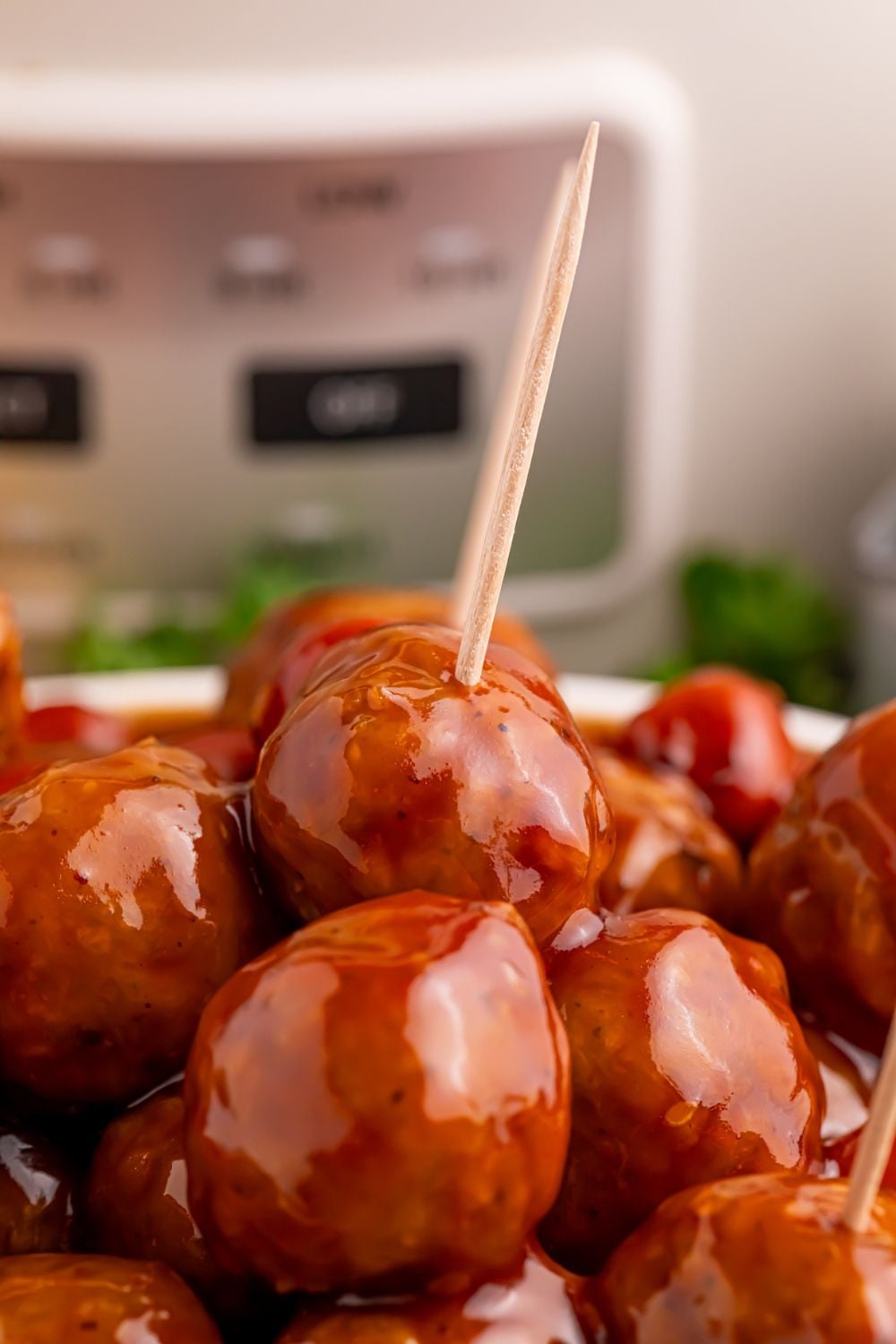 a bowl full of smokies and meatballs in sauce with a couple toothpicks poked into the meatballs 