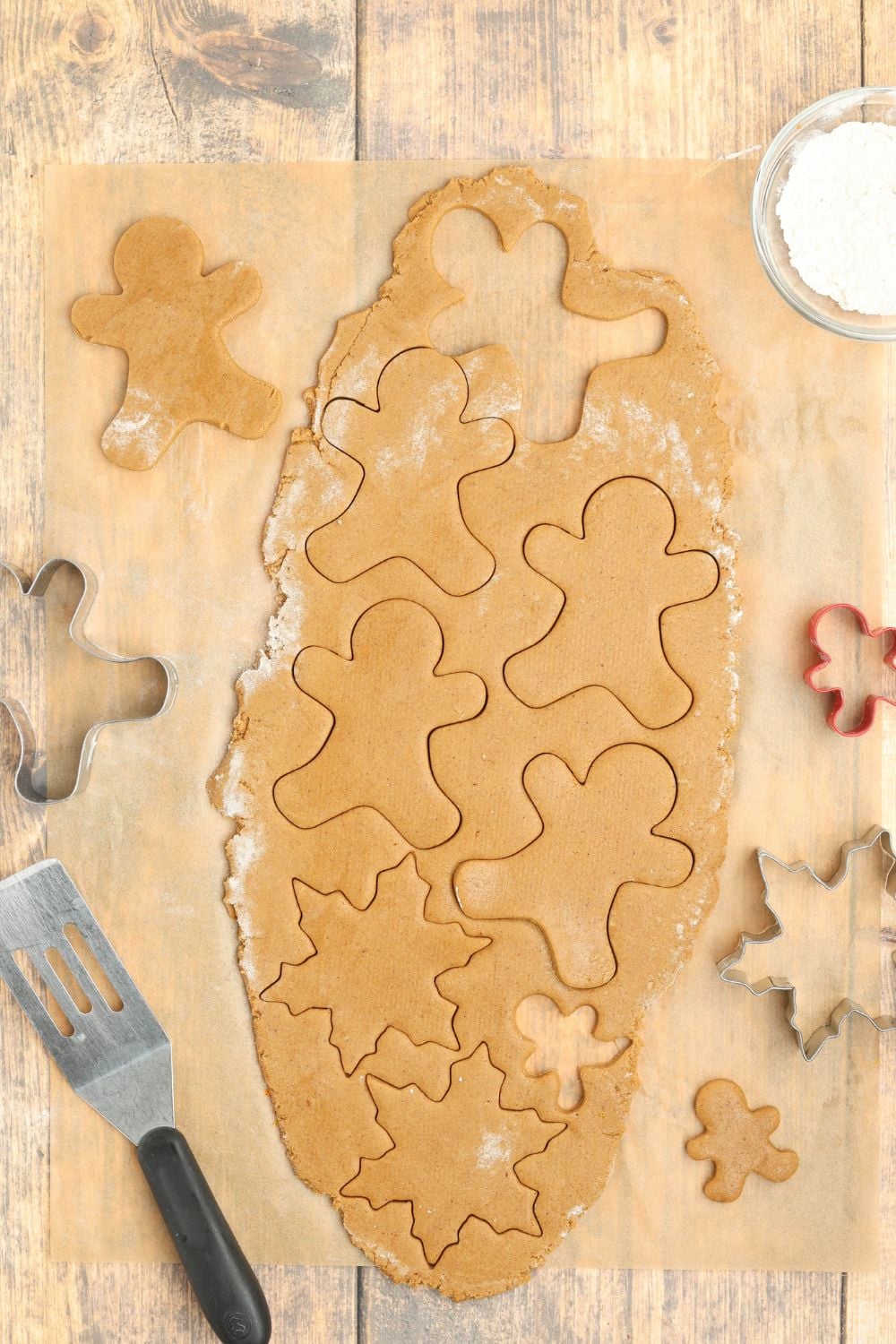 rolled out cookie dough on table with gingerbread cutouts 