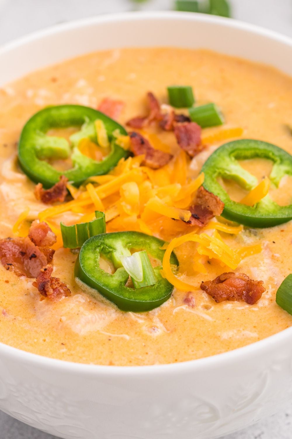 close up of jalapeno soup in a white bowl on table