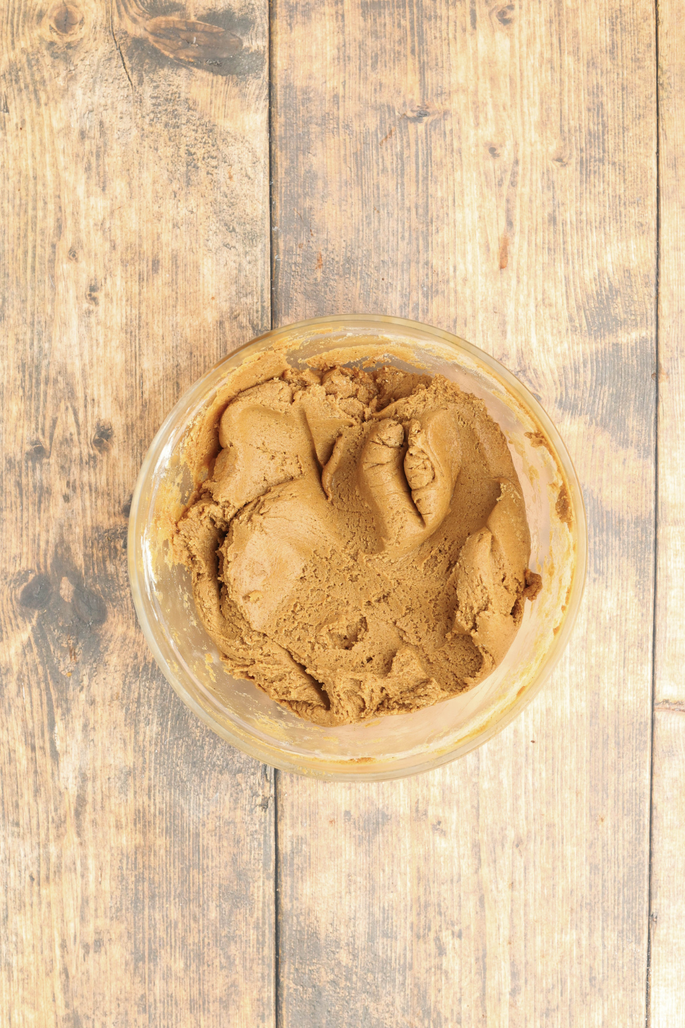glass bowl of Christmas gingerbread cookie batter on a wooden table