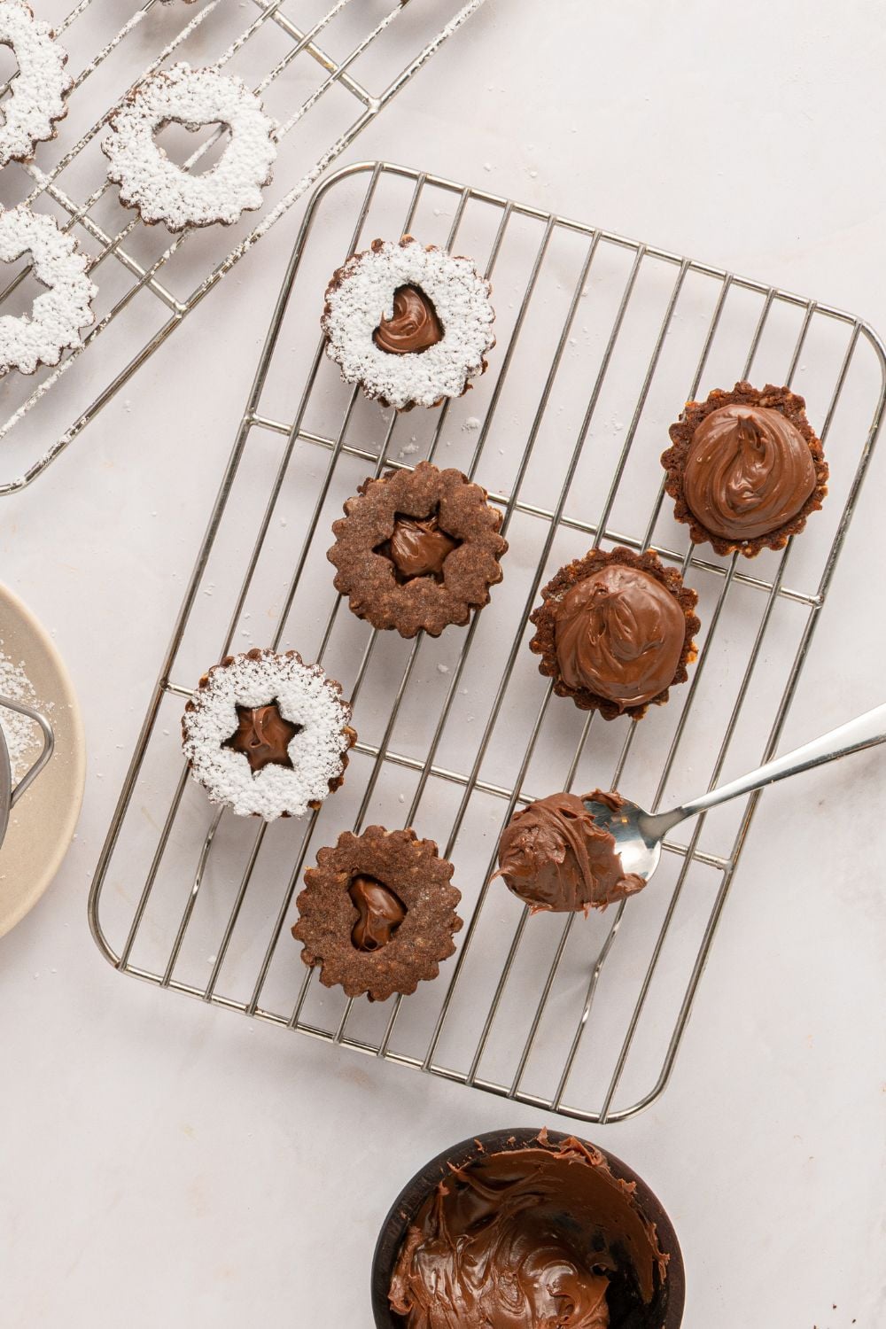 assembling sandwich Chocolate Linzer Cookies on a cooling rack 