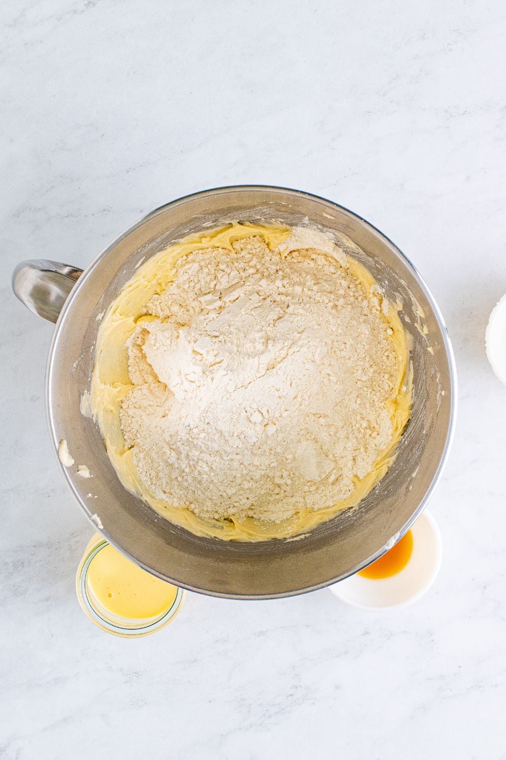 a metal mixing bowl full of creamed butter mixture and dry ingredients