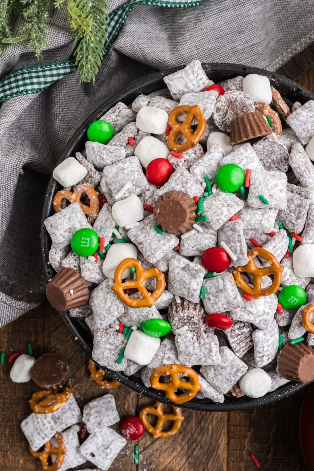 looking down on wooden table with Christmas Chex Mix in it that is loaded with crispy puppy chow