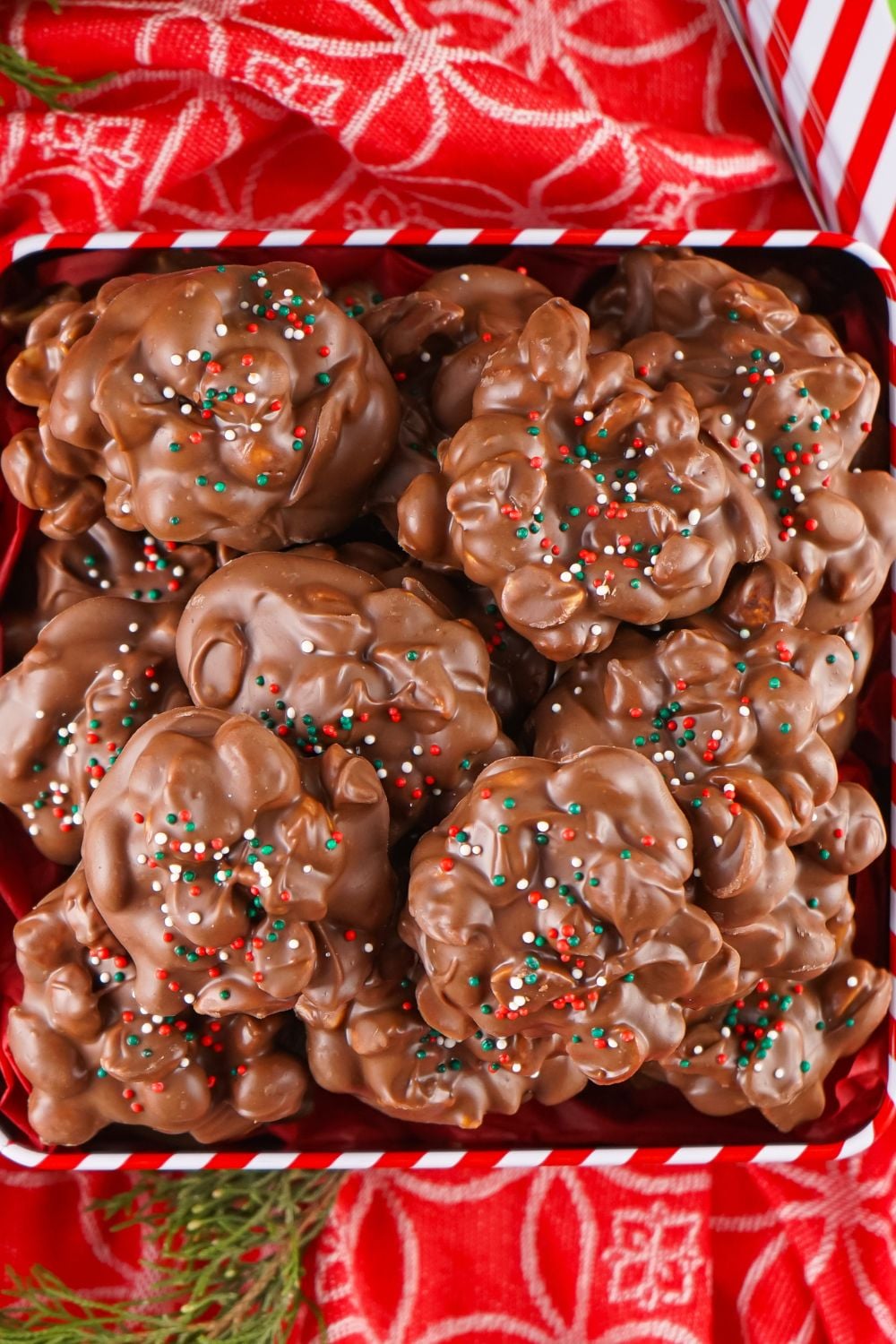 looking down on table with a red tablecloth and a box of Crockpot Christmas Candy inside that are topped with sprinkles