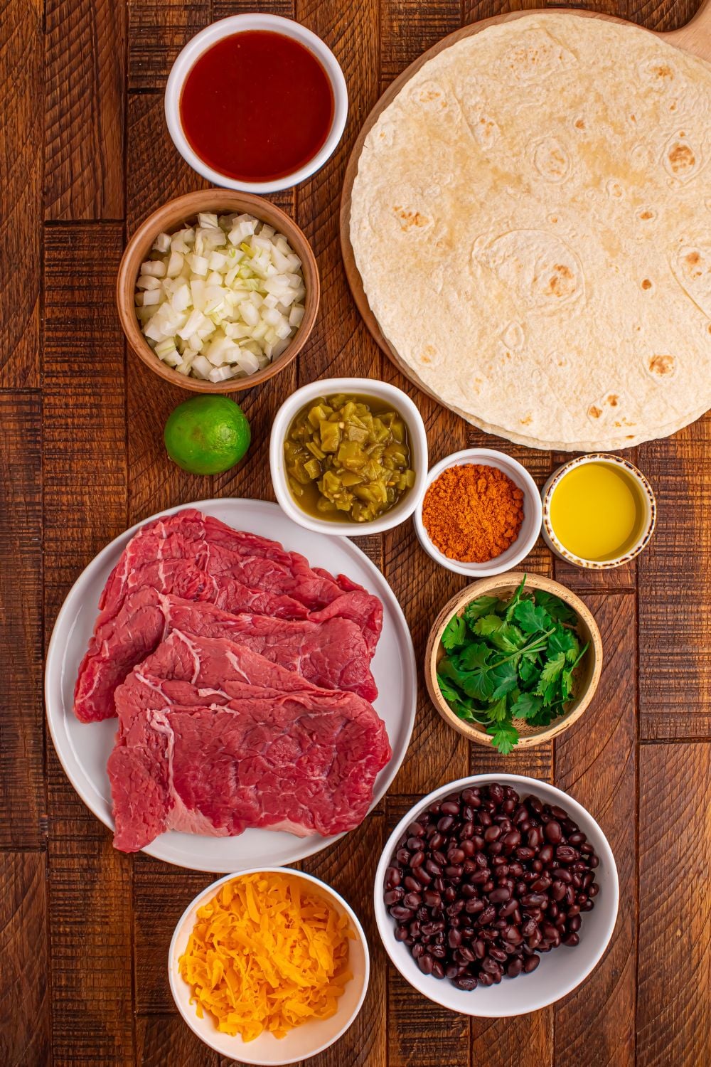 Steak Enchilada ingredients all placed on the table in bowls to show all the ingredients you will need to make the dish