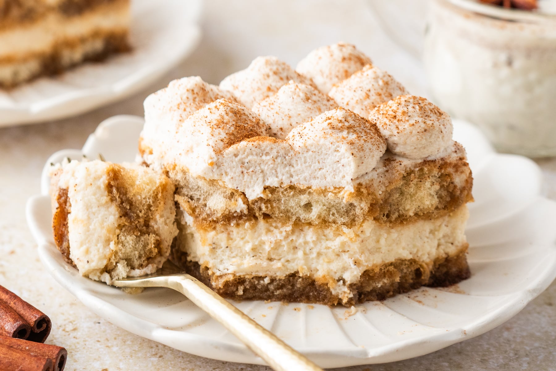 No Bake Eggnog Tiramisu sliced on white serving plates with a bite missing and with a glass of eggnog behind the plate 