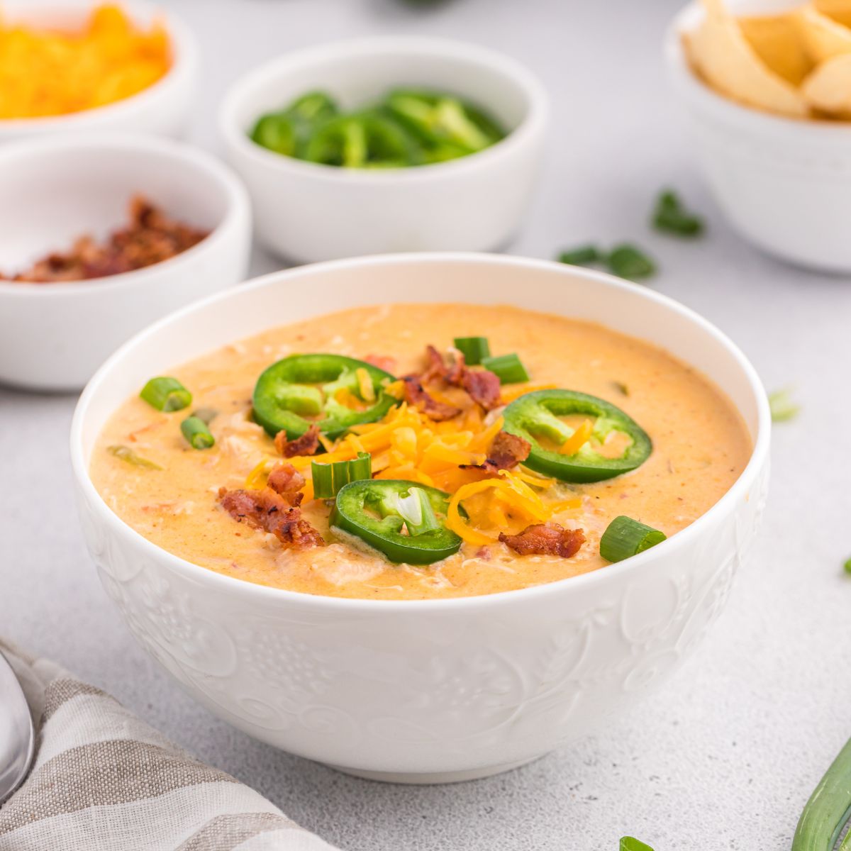 white bowls of jalapeño popper crack chicken soup with jalapenos around the soup