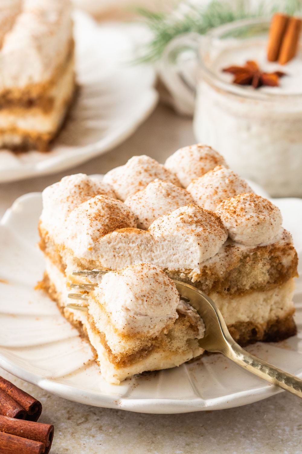 fork cutting into a slice of Eggnog Tiramisu on a white plate on table 