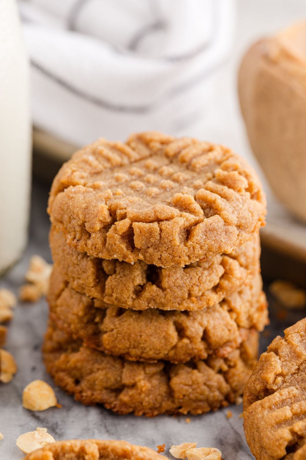 4 Ingredient Peanut Butter Cookies stacked on a table with a glass of milk to side