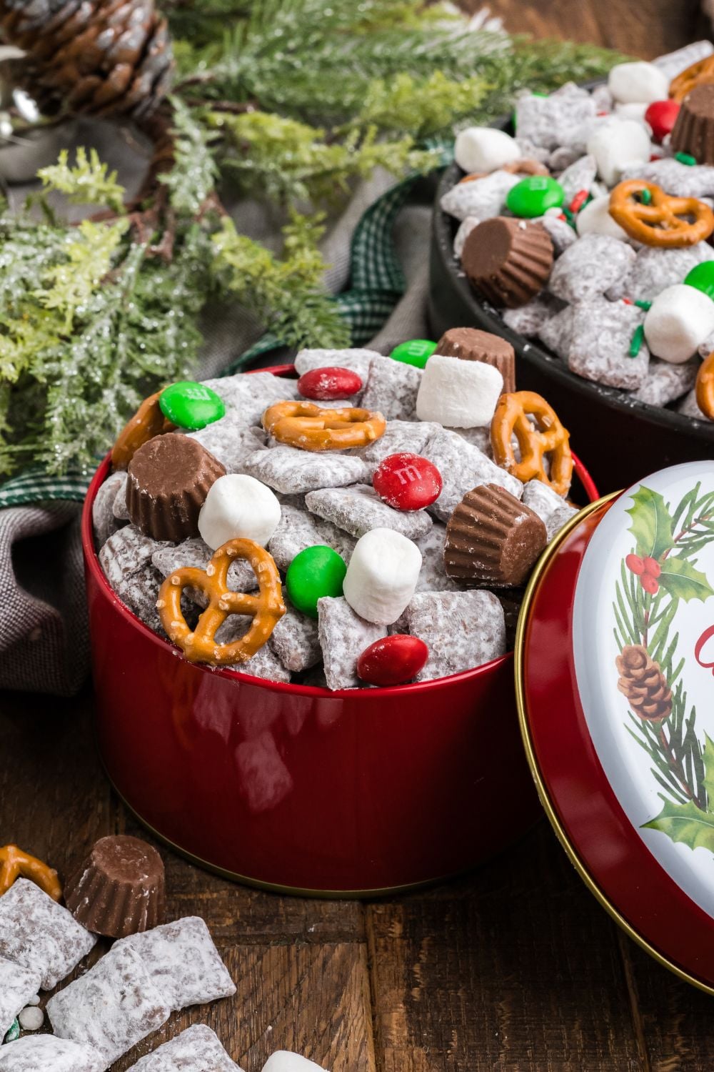 Christmas Chex Mix in bowls on table with Christmas tree limbs to side
