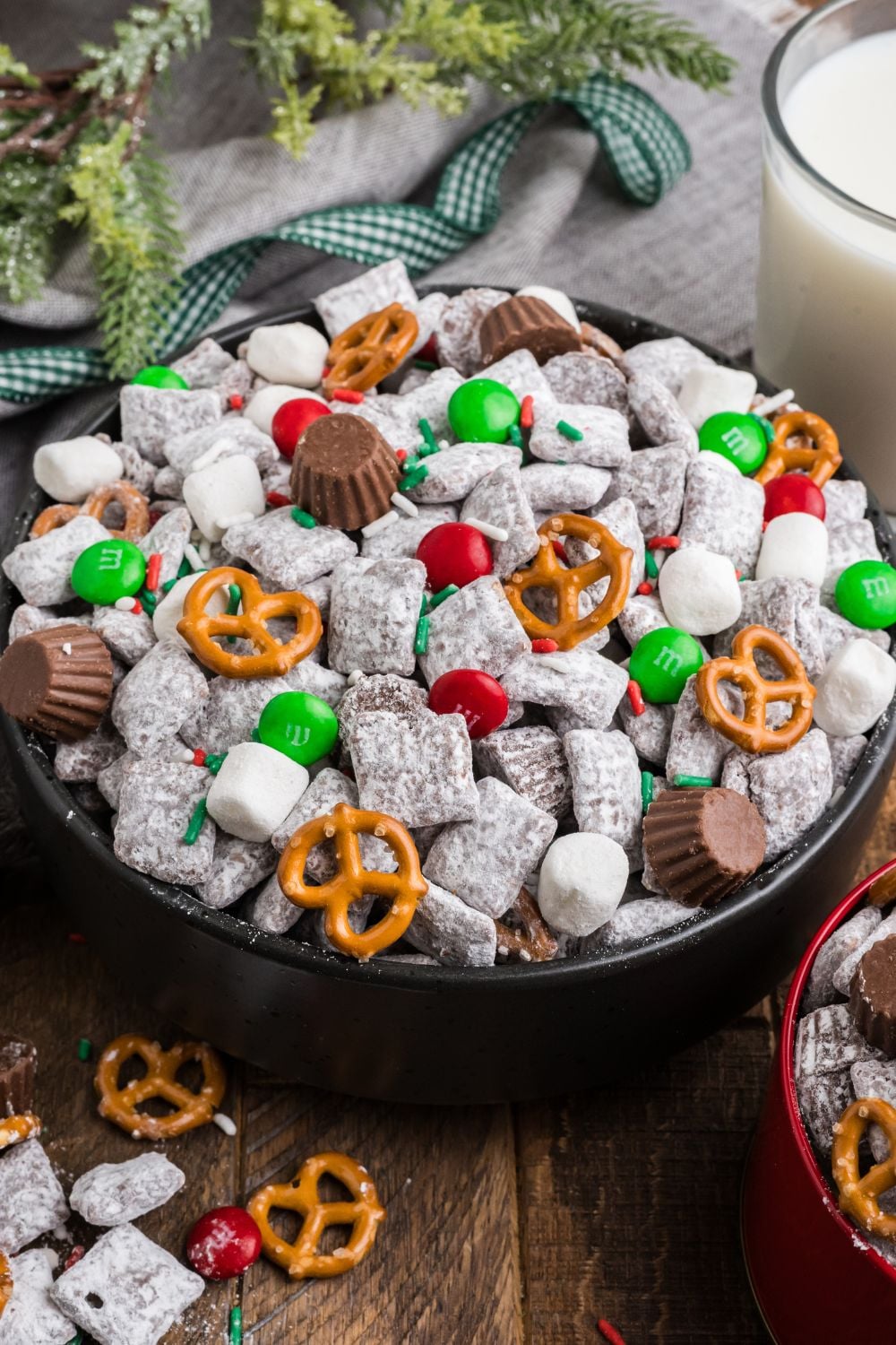 Christmas Chex Mix in a black bowl on a wooden table with Christmas decor around it on table