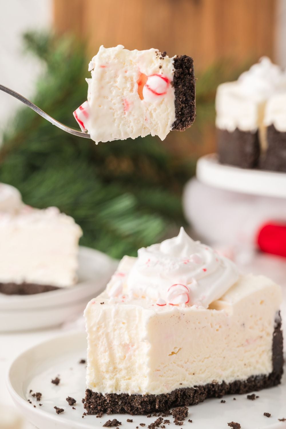 slice of No Bake Peppermint Cheesecake on a plate with a bite taken out of a piece of it 