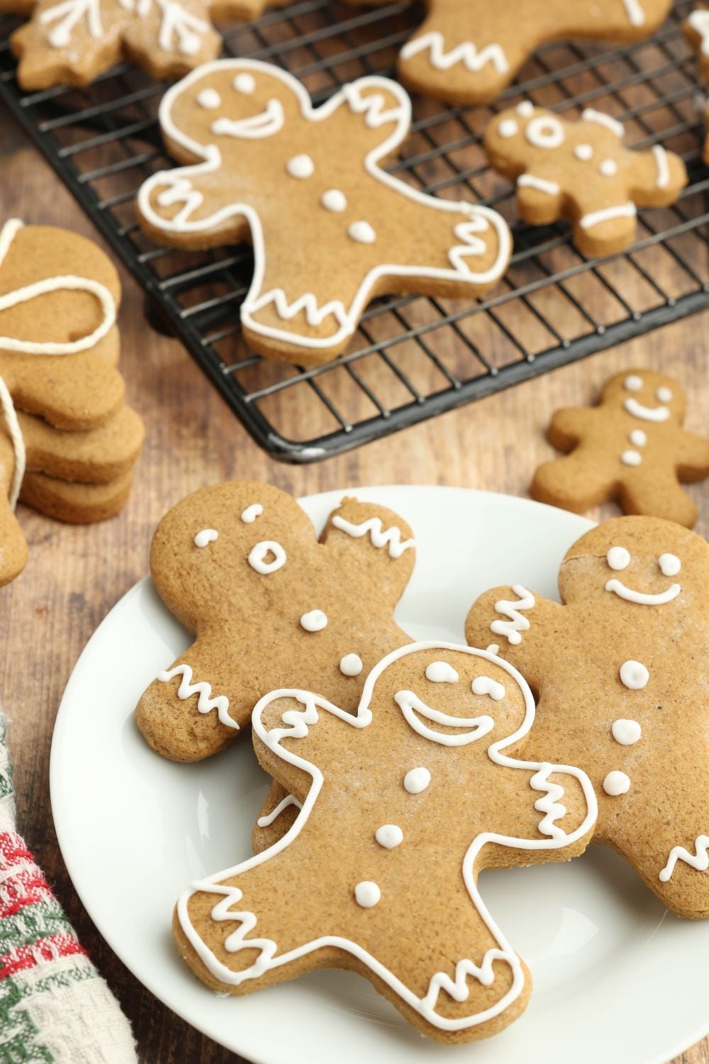 Christmas gingerbread cookies spread around the table and a cooling rack full of more cookies around the table 