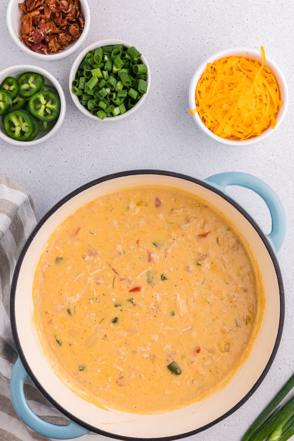 jalapeño popper crack chicken soup on table with peppers and jalapenos to side in small bowls