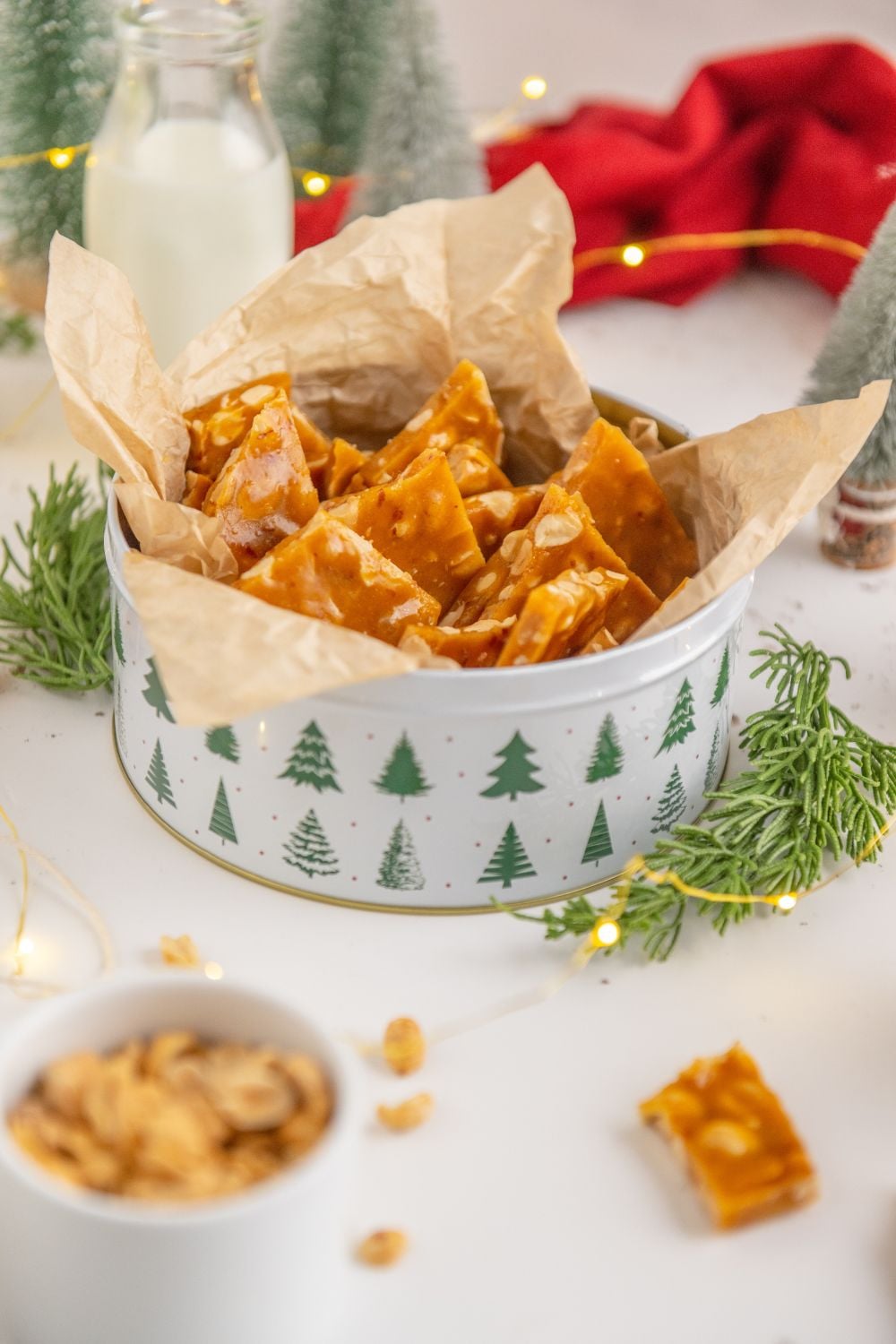 Homemade Peanut Brittle on table in a tin and more brittle around the table