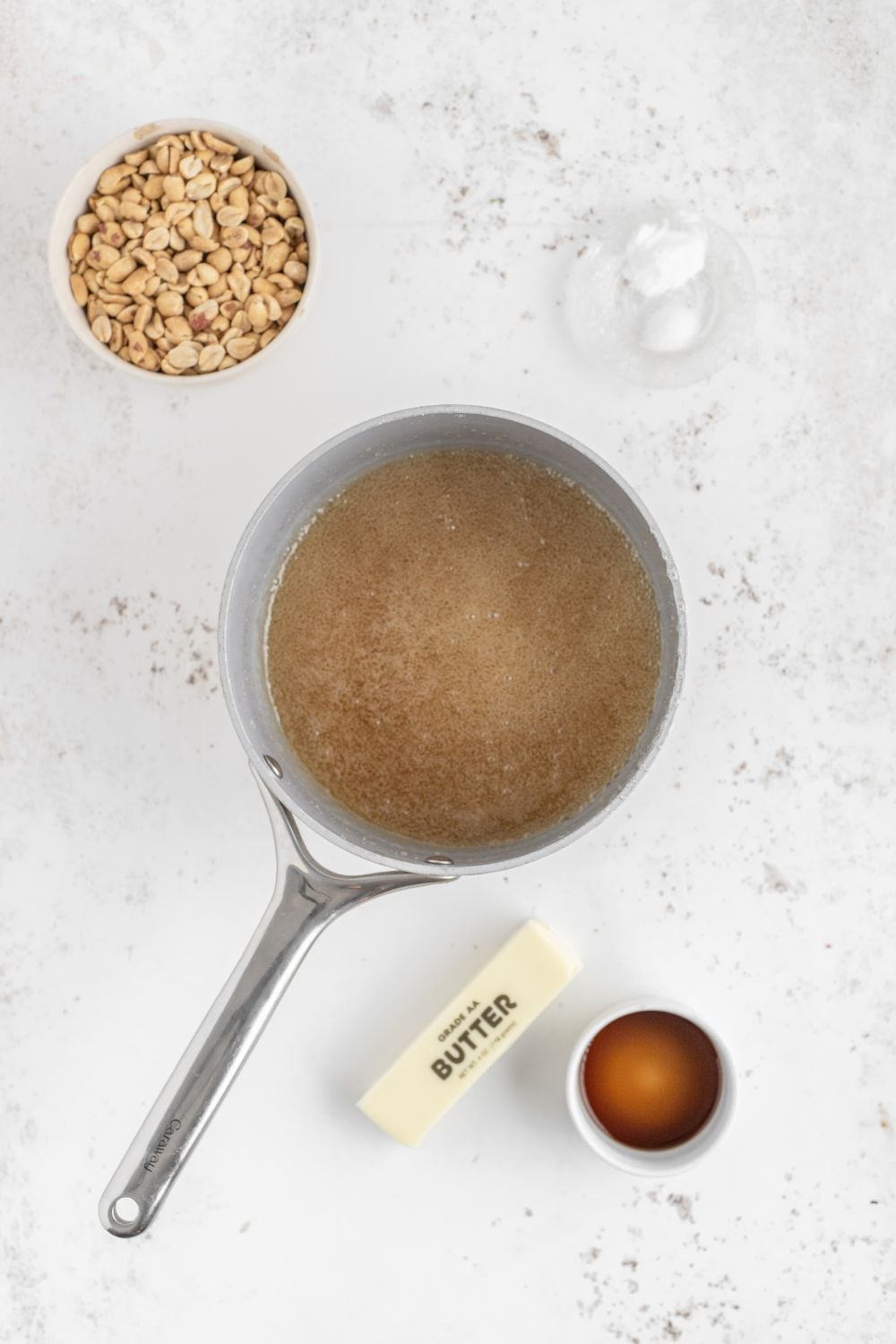prep of making Homemade Peanut Brittle in a saucepan with butter, vanilla and nuts to side