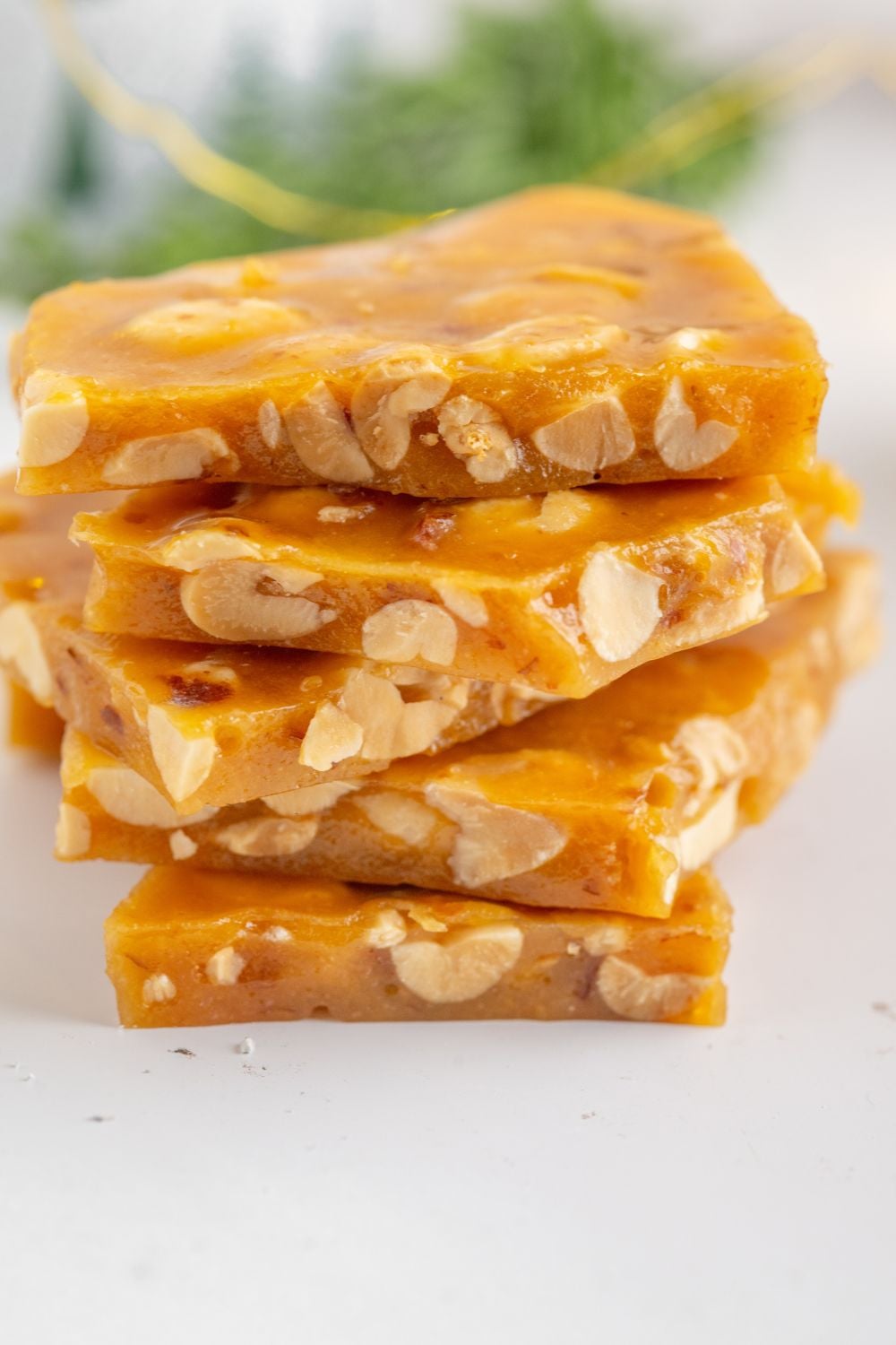Homemade Peanut Brittle stacked on a white table