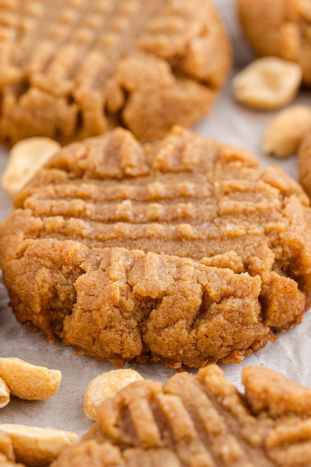 4 Ingredient Peanut Butter Cookies spread out around the table with peanuts all around to show they are peanut cookies