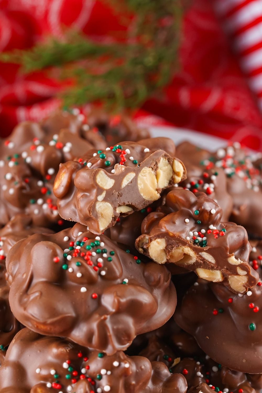 close up of Crockpot Christmas Candy stacked on plate with one cut in half to show the nuts in chocolate
