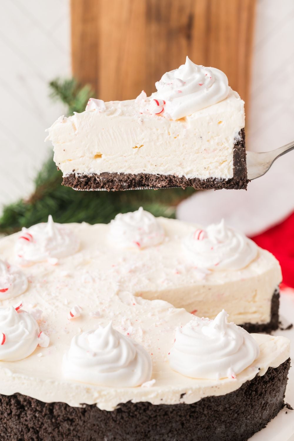 slice of No Bake Peppermint Cheesecake being lifted up on cheesecake platter 