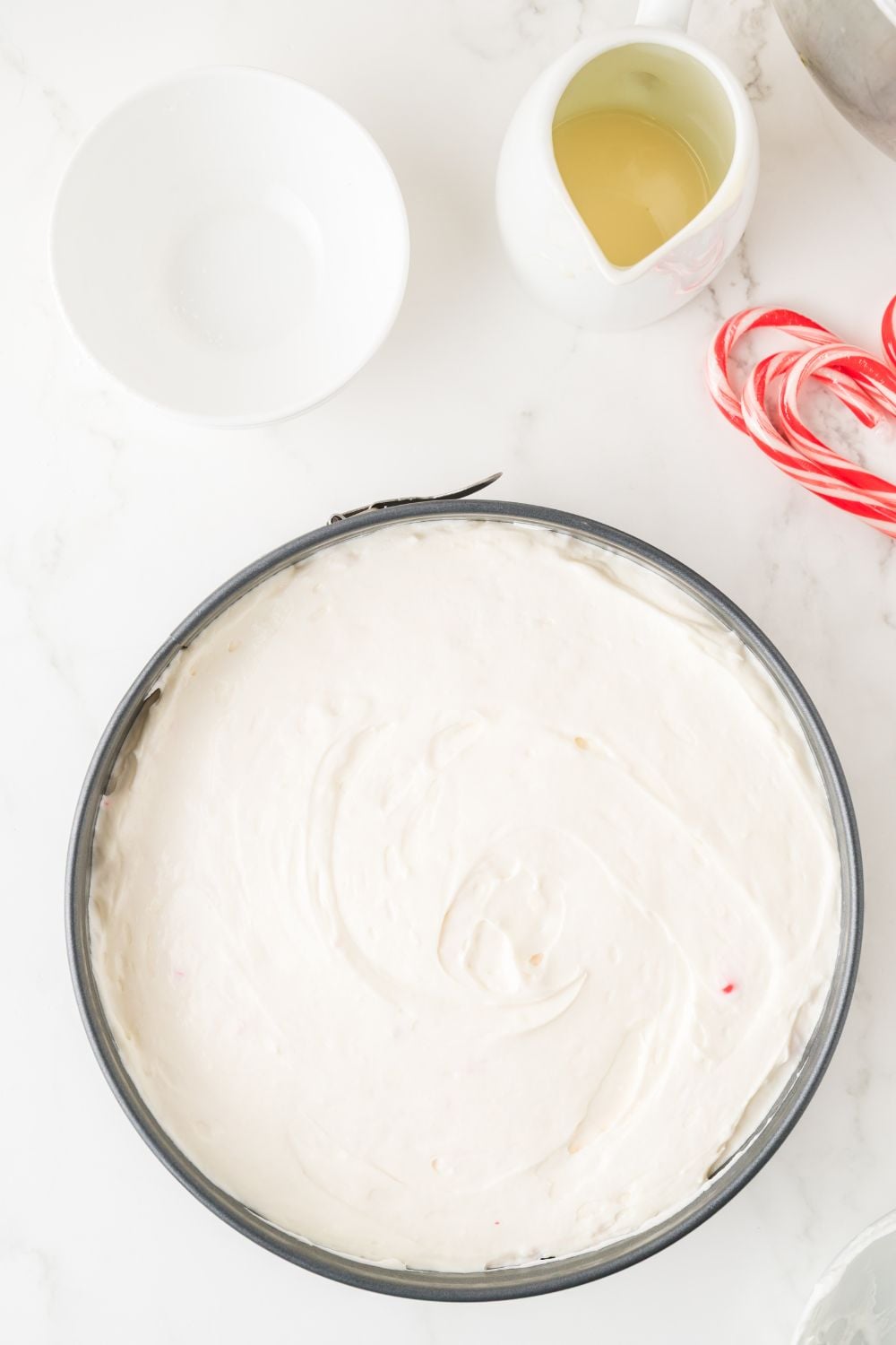 No Bake Peppermint Cheesecake in a cheesecake pan on table with topping ingredients on the table 