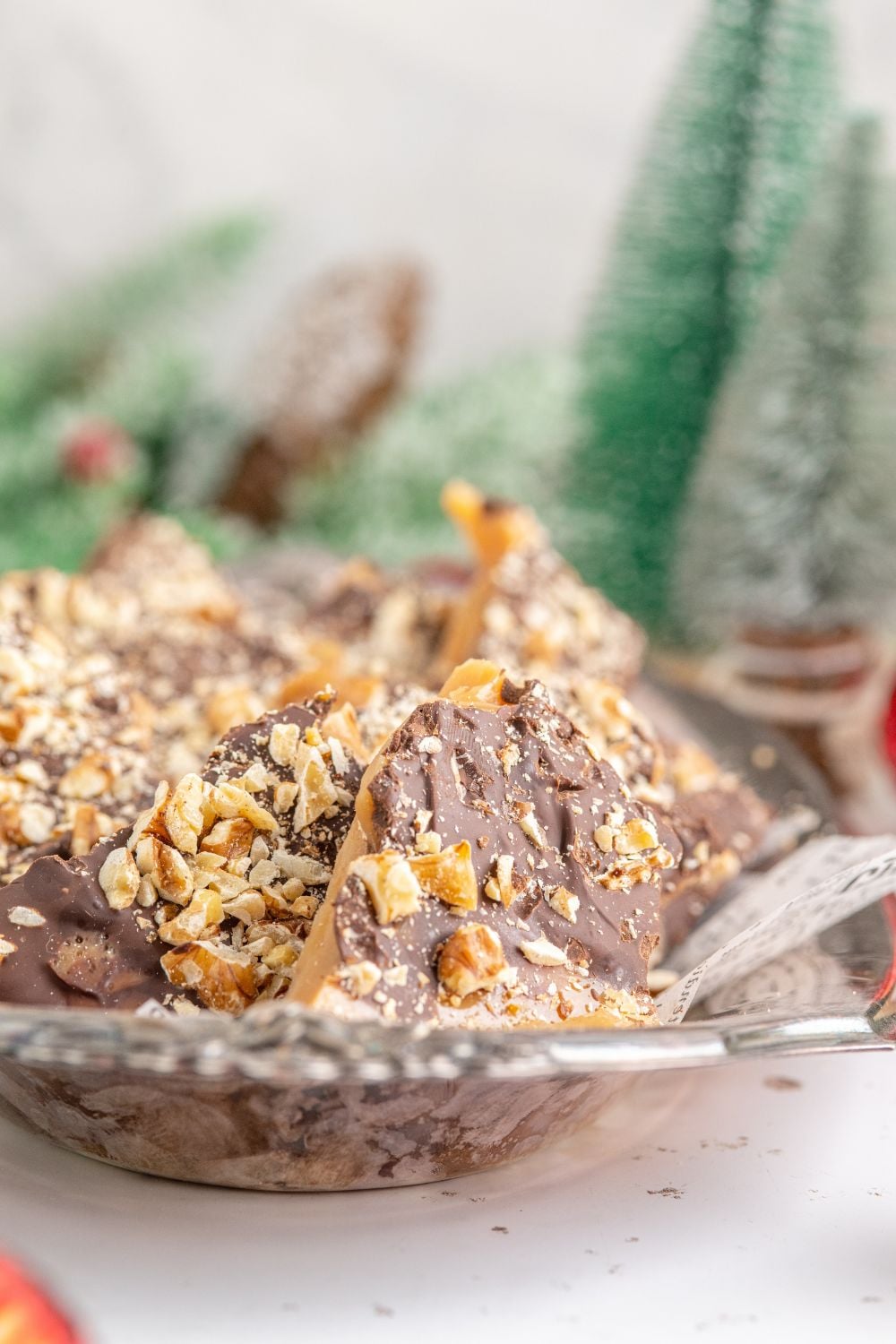 English Toffee on a silver platter with Christmas trees behind it on the table