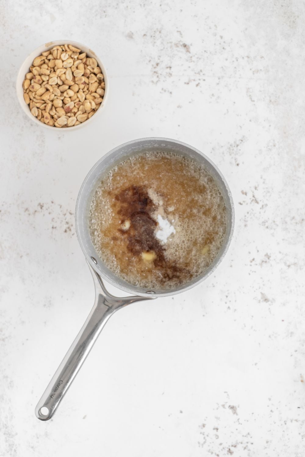 process of making Homemade Peanut Brittle with peanuts in a bowl to side