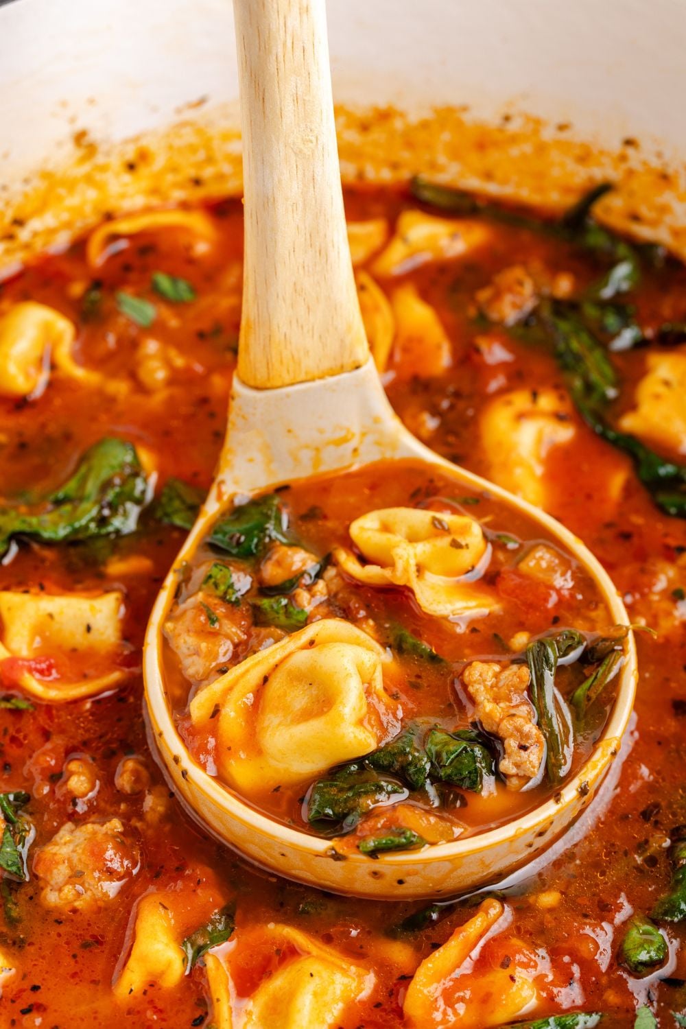 Sausage Tortellini Soup in a pot with a ladle lifting out of the pot that is full of the tortellini soup