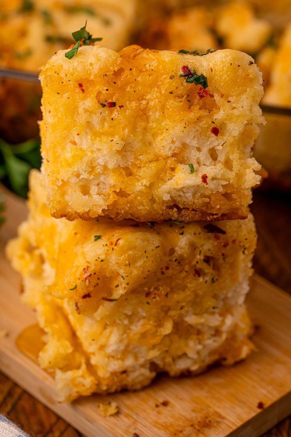stacked biscuits placed on top of one another with more biscuits placed in a pan behind it