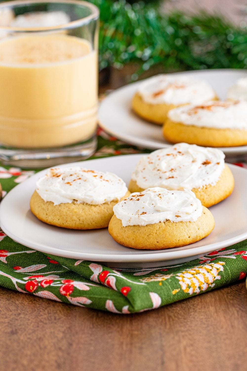 plates full of cookies with eggnog to side in a clear glass and a green towel under the plate