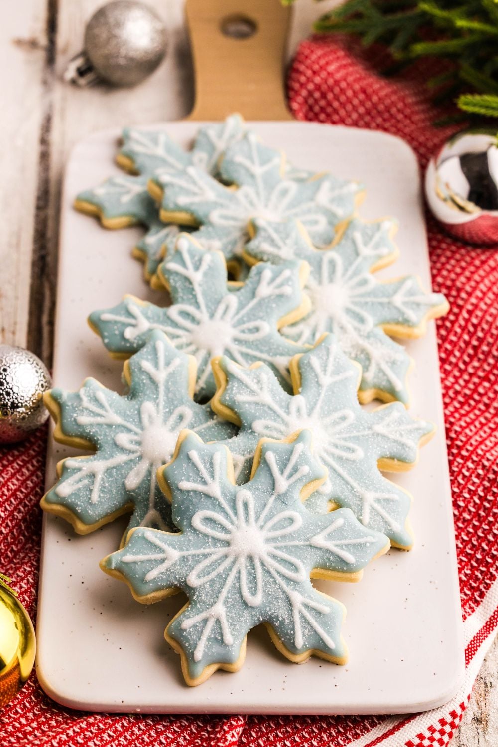 snowflake shaped sugar cookies on a long tray on table with Christmas decorations around the table