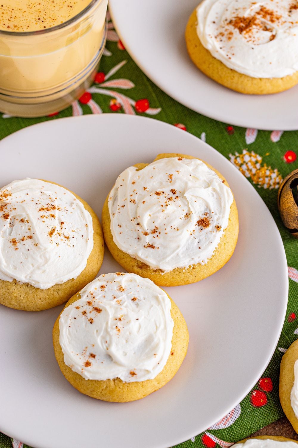 two white plates with eggnog cookies on table and glass of eggnog to side