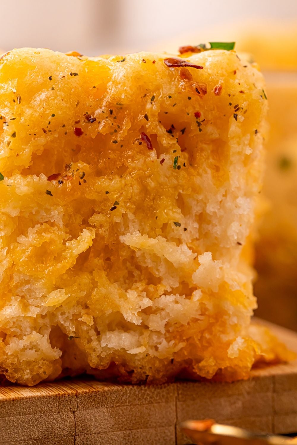 close up view of a Cowboy Butter Swim Biscuit on a wooden cutting board showing how fluffy it is and full of spices and seasoning